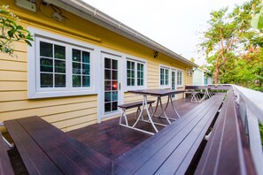 A yellow building with a wooden deck and outdoor seating. - Varee Valley Resort and Restaurant (Ubolratana)