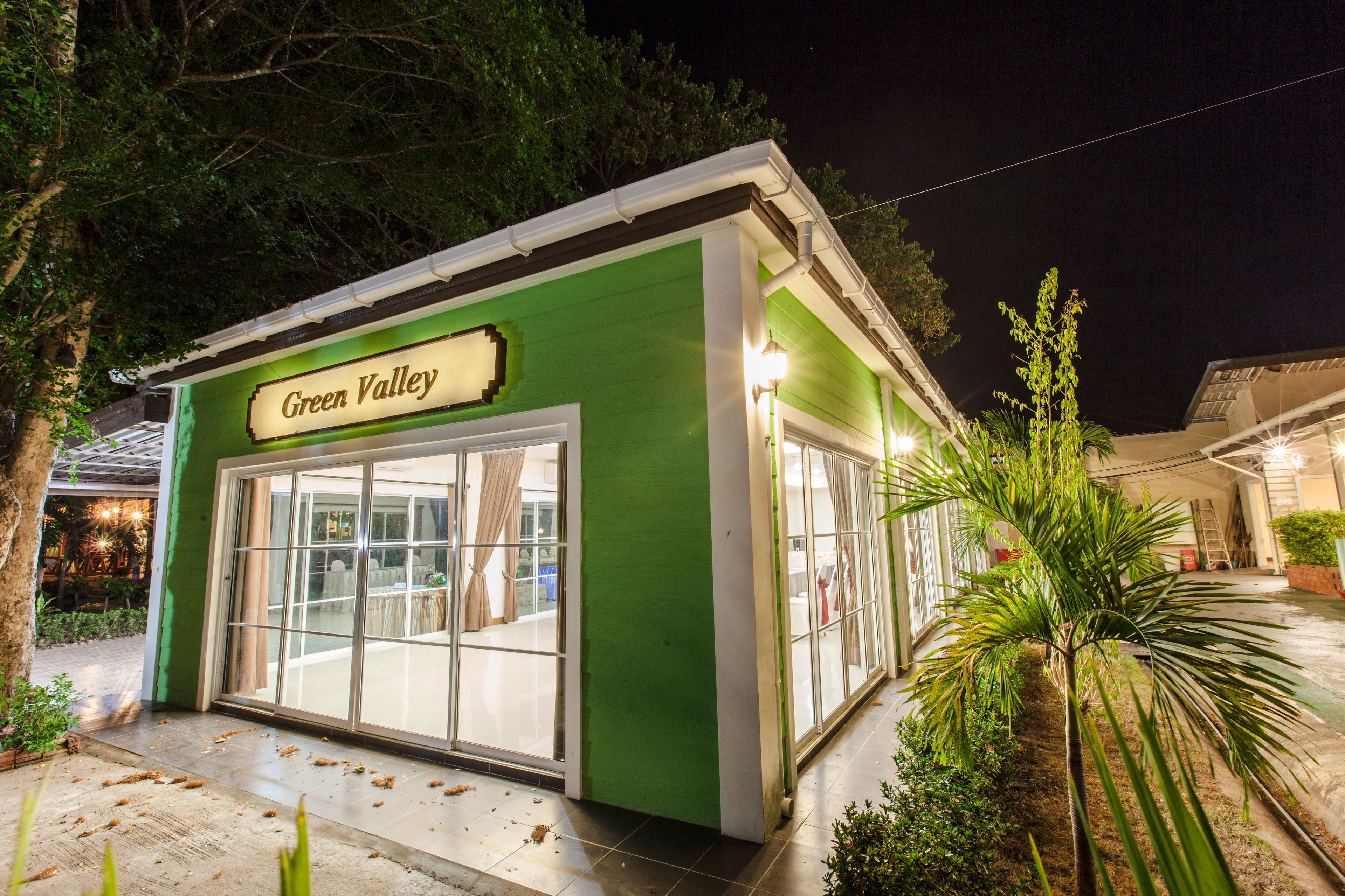 A green building with a sign reading "Green Valley" and large glass doors.