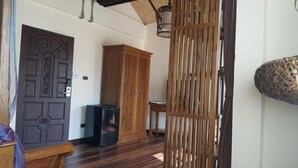 A wooden door, a cabinet, and a woven partition in a room with wooden flooring. - Yi's Garden Villa (Chiang Mai)
