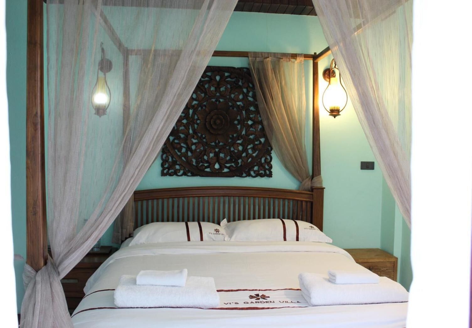A bed with a canopy, a decorative wall hanging, and a bedside lamp.