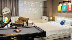 Una habitación de hotel moderna con una cama, un escritorio con mesa de billar, una pantalla de proyector y una lámpara en el techo.