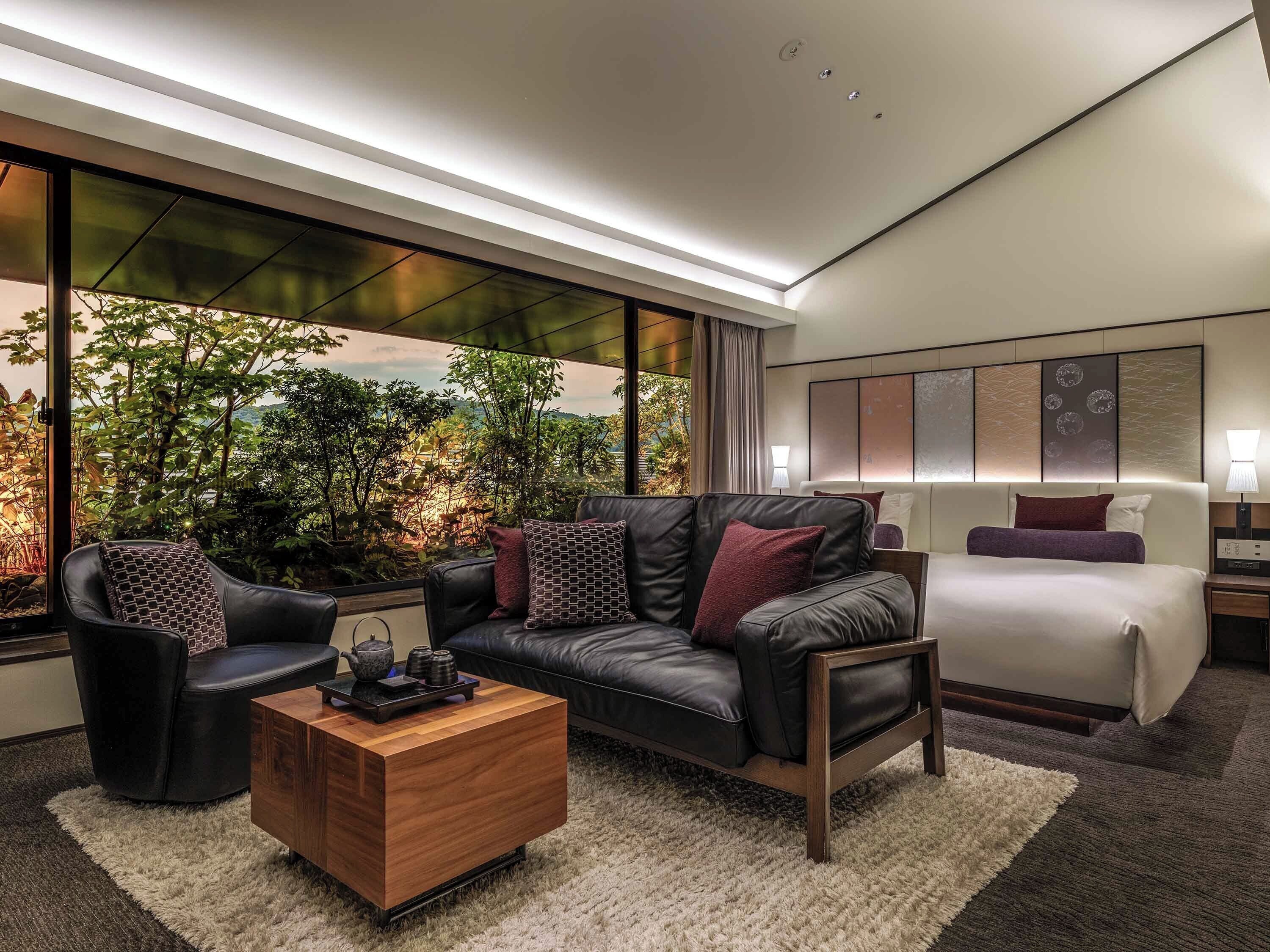 Une chambre d’hôtel moderne avec un canapé en cuir, une table basse en bois et un lit doté d’une tête de lit.
