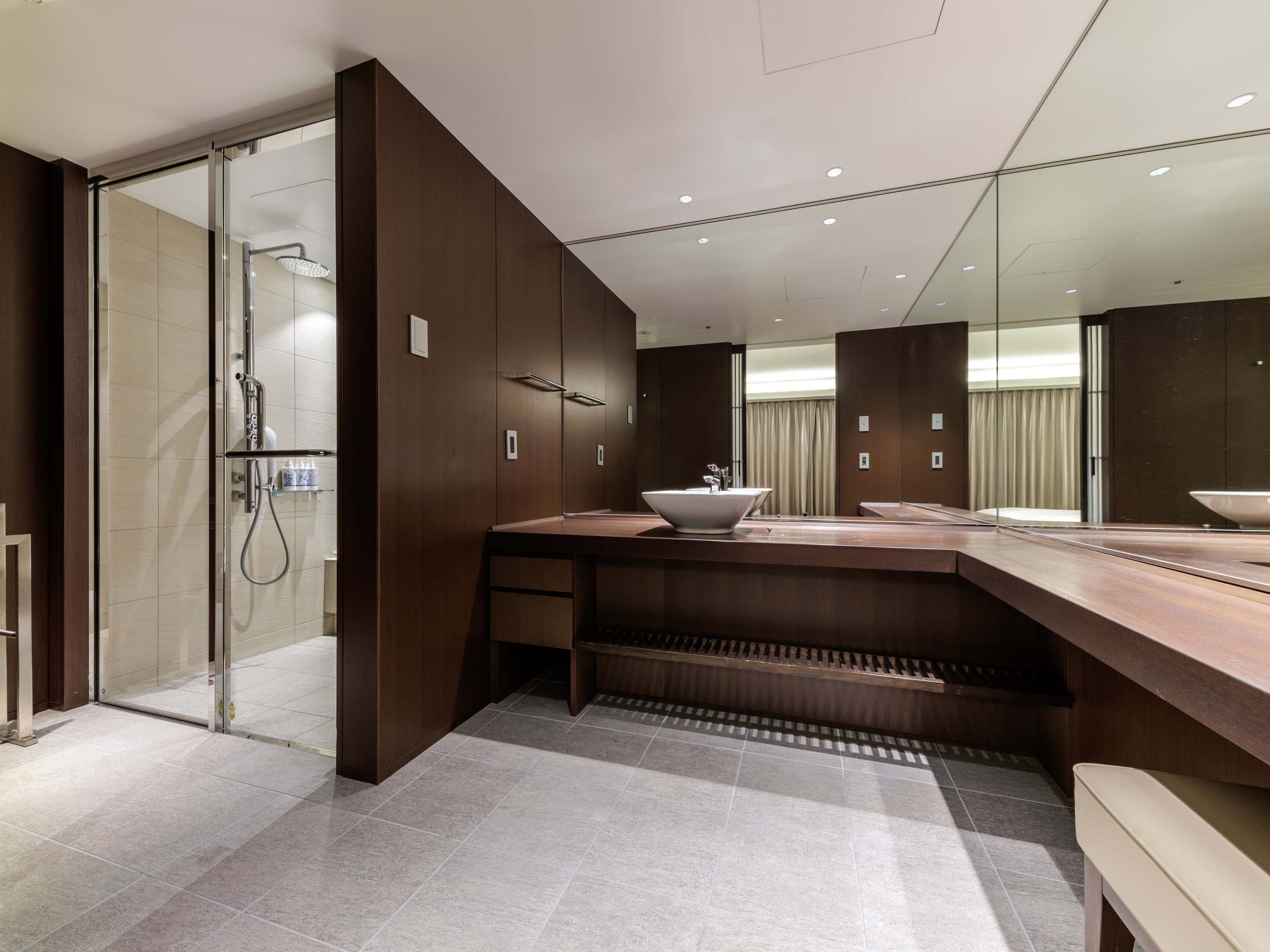 Une salle de bain moderne dotée d’une douche à parois de verre, d’un grand miroir et d’un meuble-lavabo avec un vasque posée.