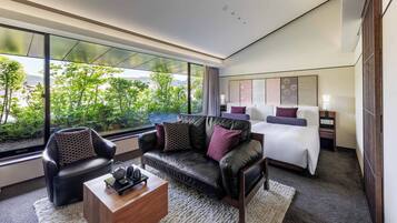A modern hotel room with a large window, a bed, a sofa, and a coffee table.