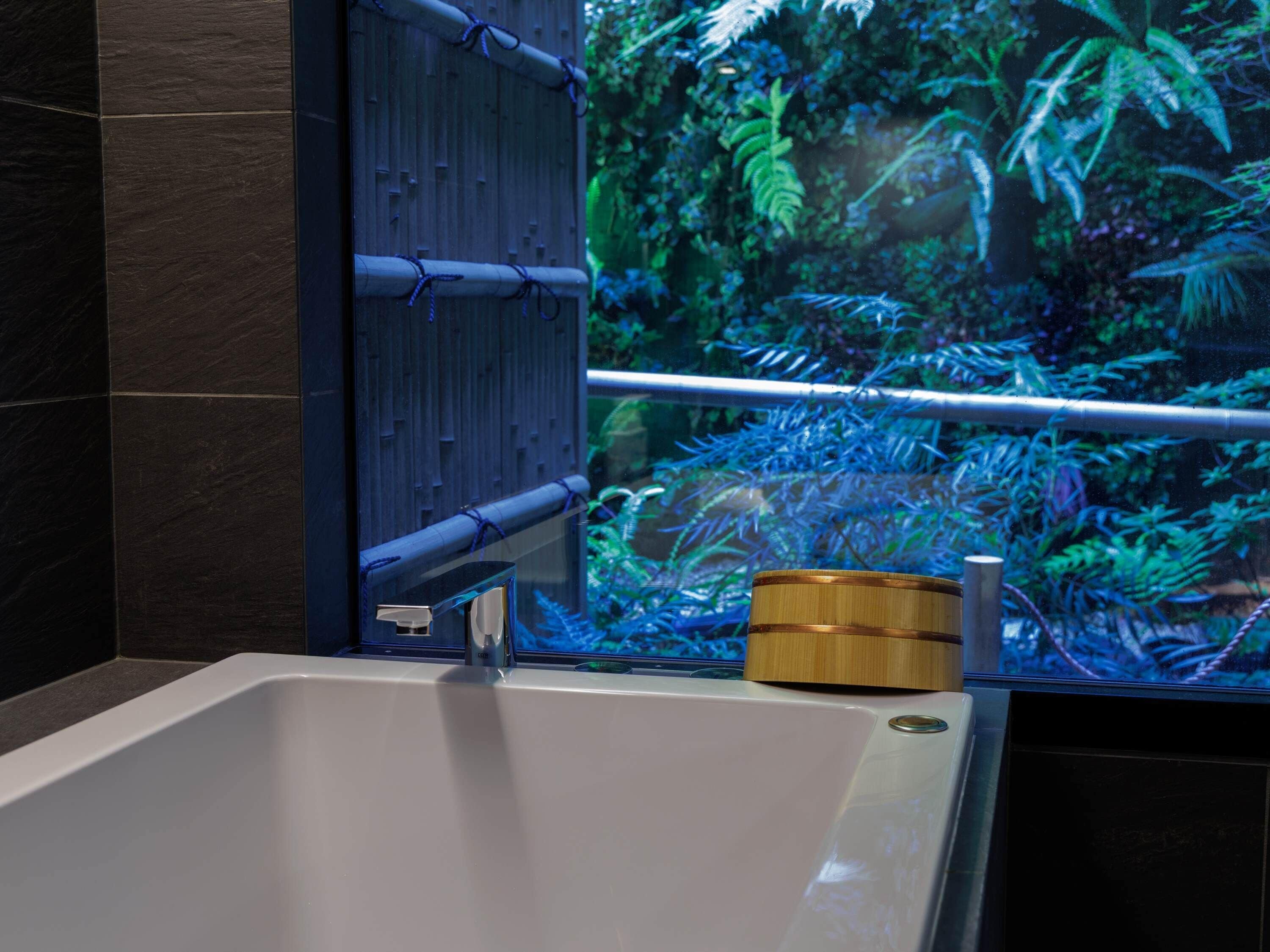 A bathtub with a bamboo mat and a wooden container.