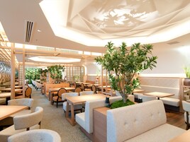 A modern restaurant interior with wooden furniture, green plants, and a ceiling with a leaf pattern.