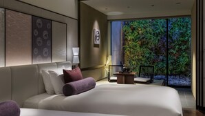 A modern hotel room with a large bed, a small side table, a nightstand, and a view of a lush indoor garden through a glass door. - SOLARIA Nishitetsu Hotel Kyoto Premier (Kyoto)