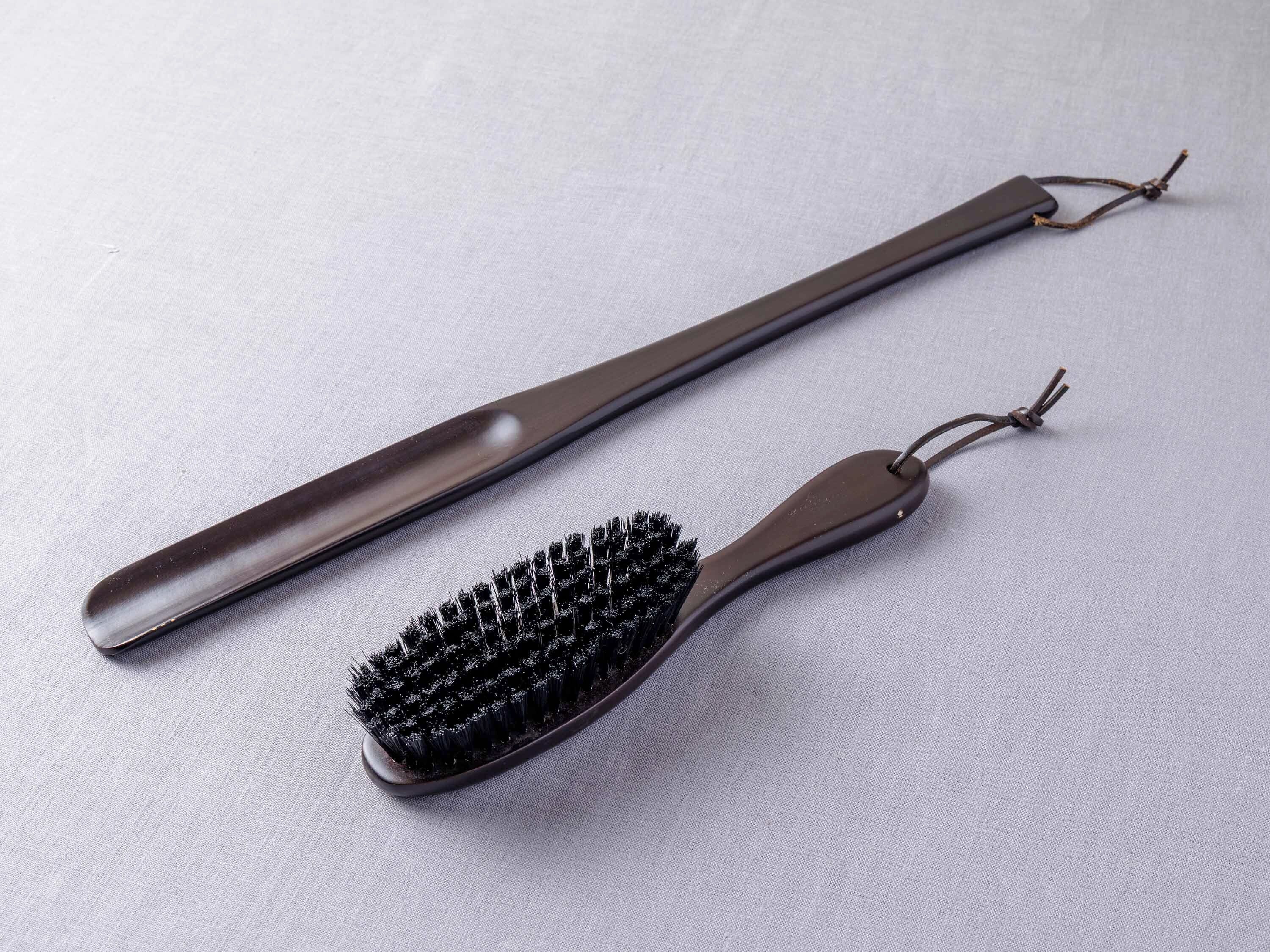 A hairbrush with a long handle and a smaller brush head with dense bristles.