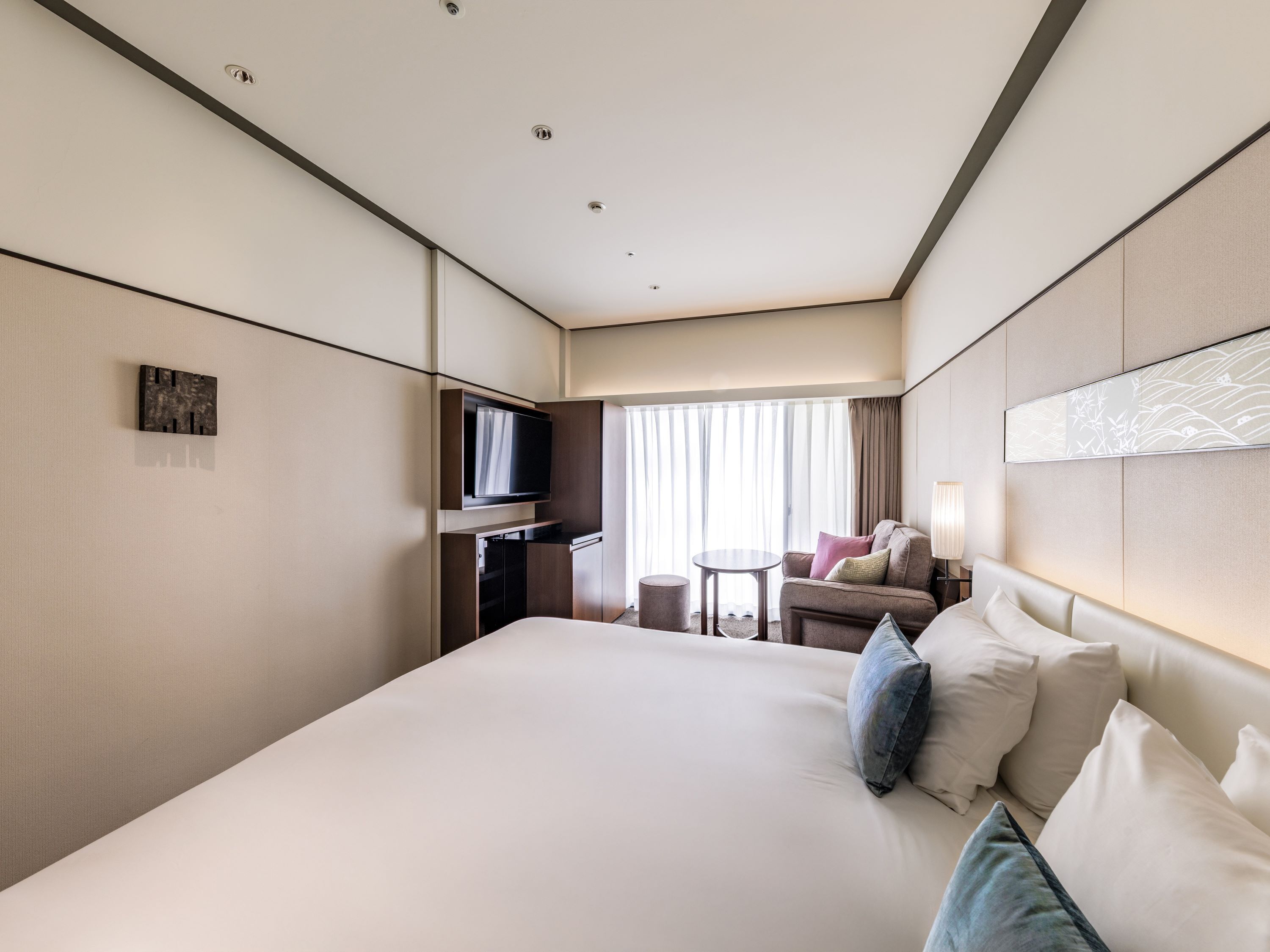 A hotel room with a large bed, a television, a small table, and a sofa.