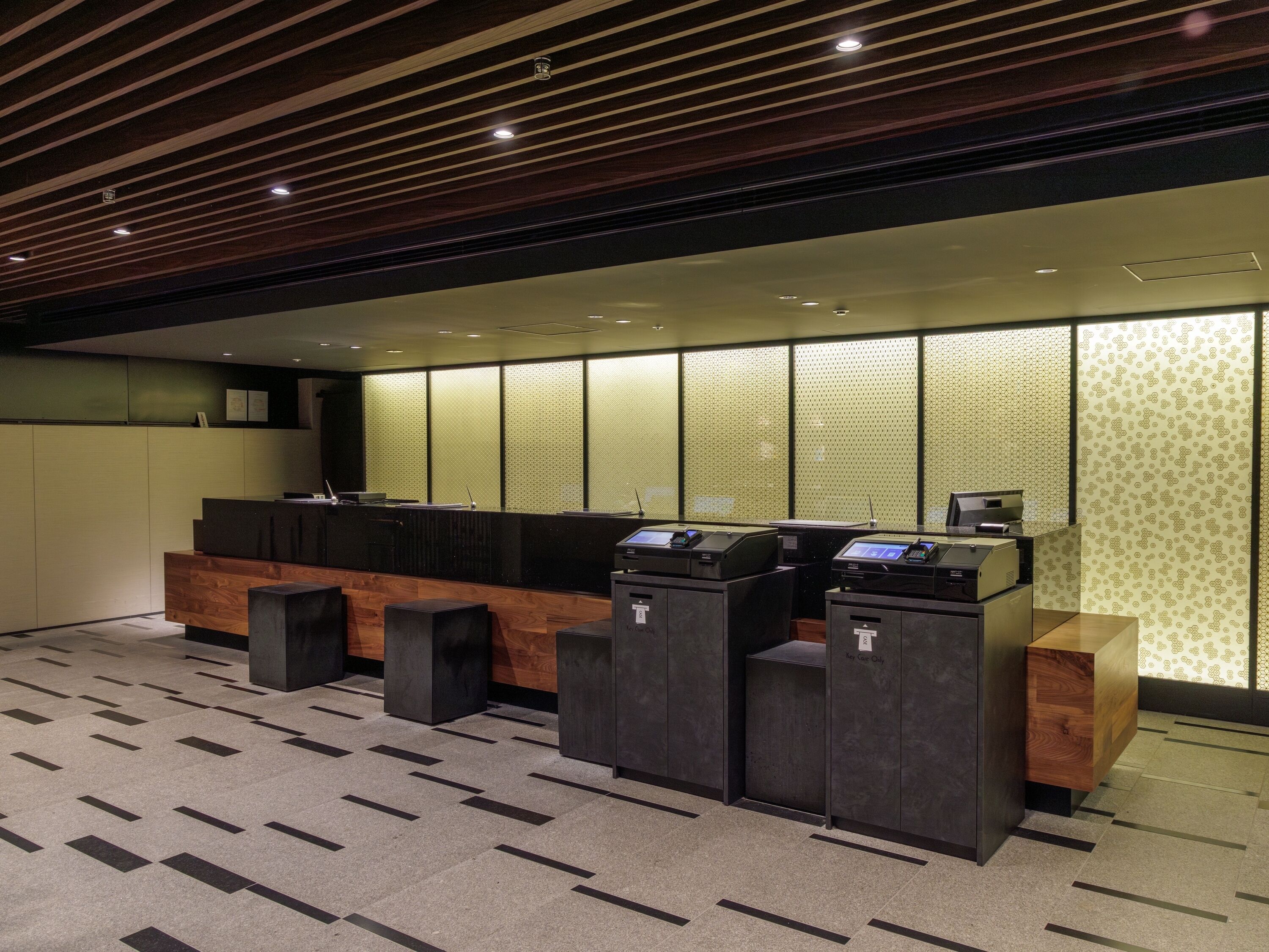 A reception area with a wooden reception desk, a seating area, and a patterned wall.