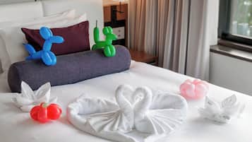 A hotel room with a neatly made bed, pillows, and decorative balloons.