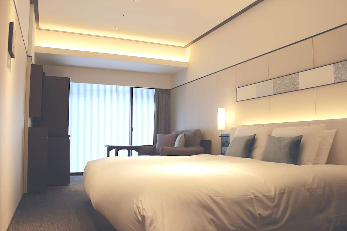 A modern hotel room with a large bed, a desk, and a chair.