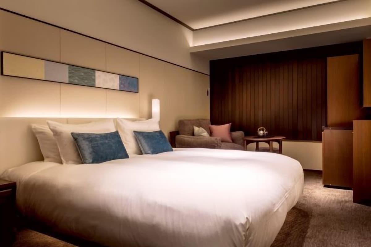 A hotel room with a large bed, a sofa, a small table, and a cabinet.