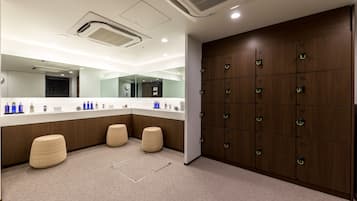 A modern bathroom with a large mirror, multiple lockers, and a counter with toiletries.