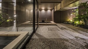 A modern indoor space with a glass partition, a wooden bench, and a small garden area with plants. - SOLARIA Nishitetsu Hotel Kyoto Premier (Kyoto)