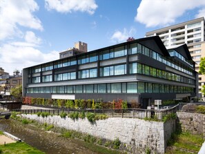 A modern multi-story building with large windows and a stone retaining wall. - SOLARIA Nishitetsu Hotel Kyoto Premier (Kyoto)