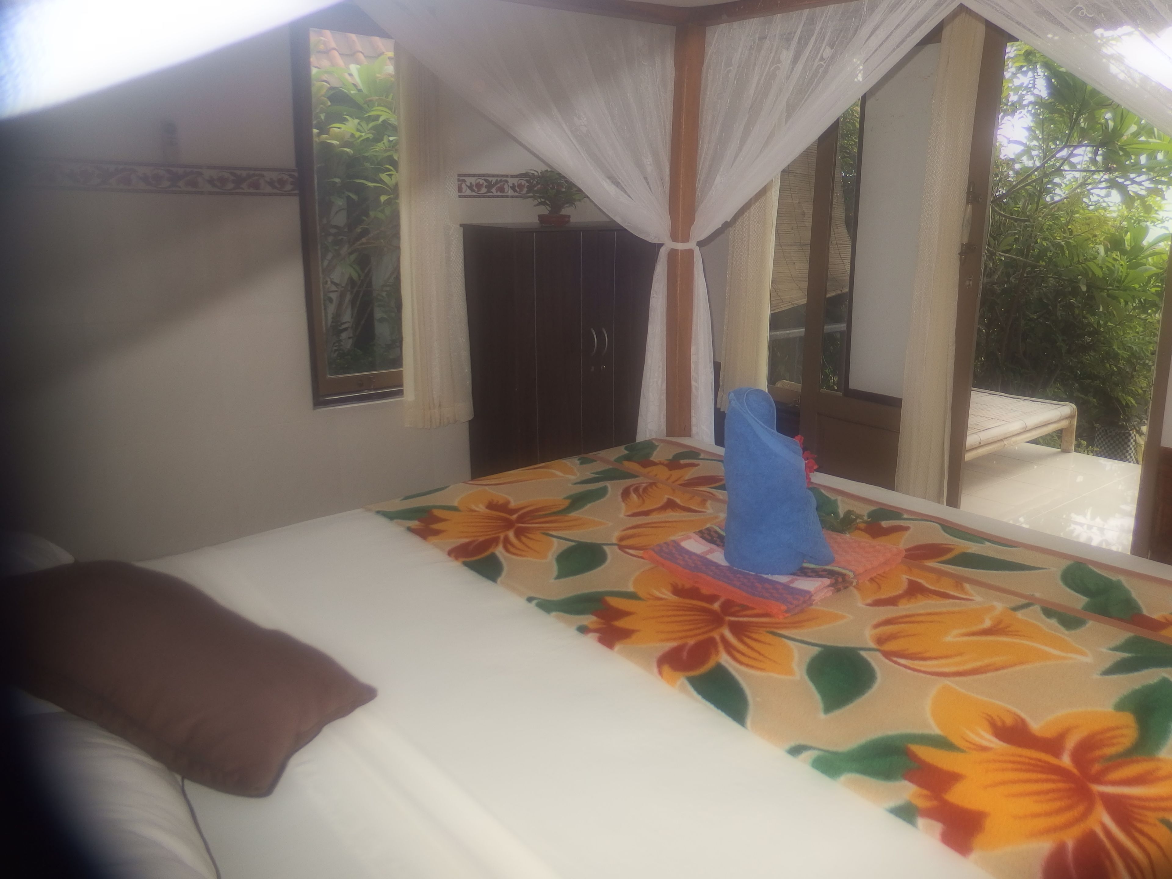 Un dormitorio con cama, mesita de noche, planta en maceta y ventana con vistas al verdor.
