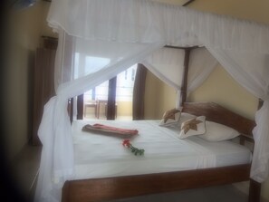 A bed with a canopy, wooden headboard, and pillows with floral designs. - Bukit Indah Home Stay (Karangasem)
