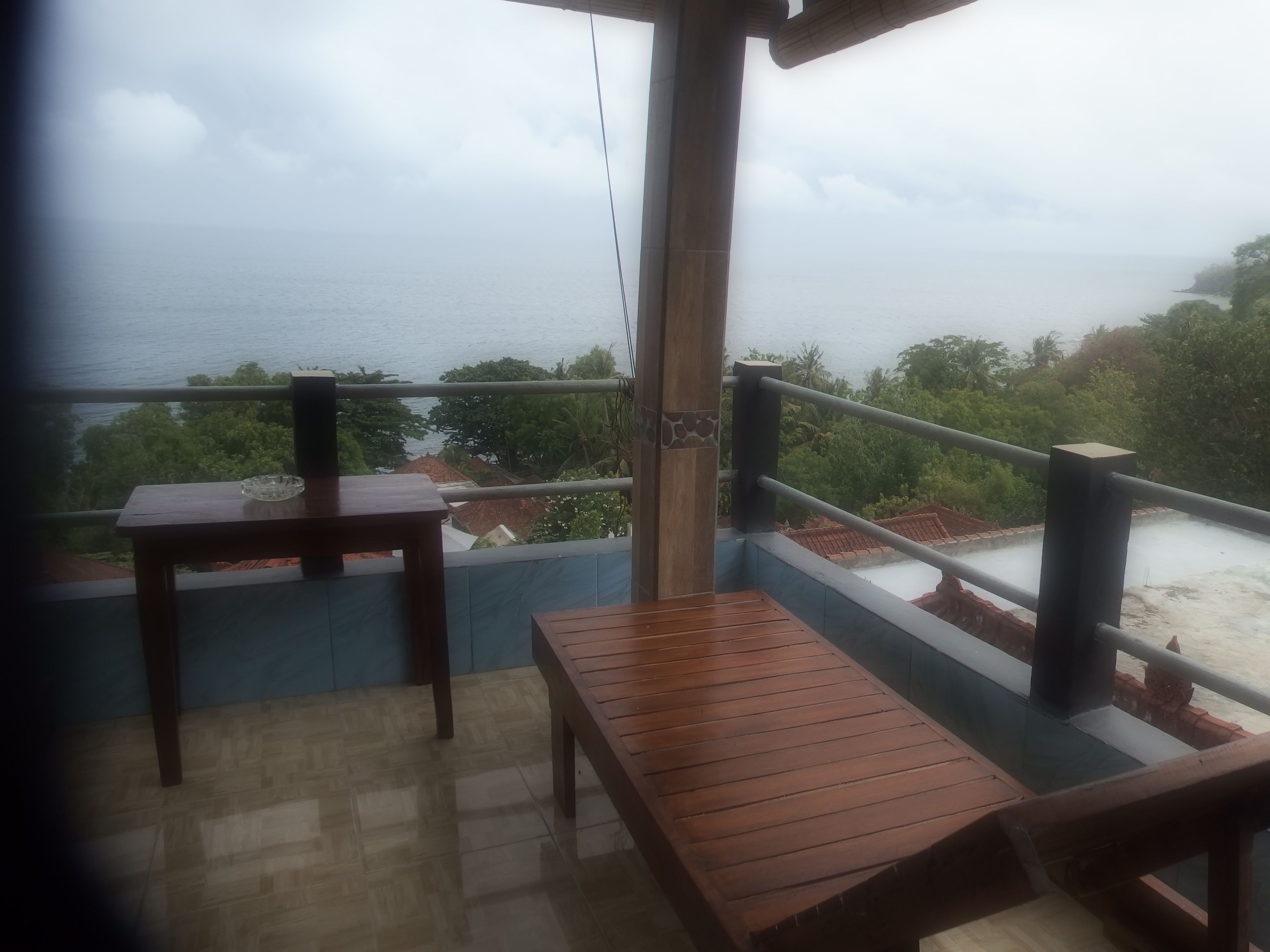 Un balcón con muebles de madera y vista al mar.
