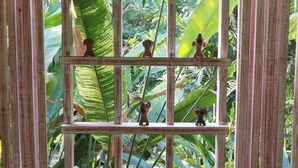 Una repisa de madera con figuritas sobre un fondo de frondosa vegetación.