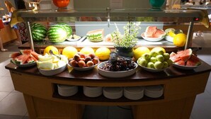 A buffet counter with various fruits and vegetables, including watermelon, lemons, and grapes.