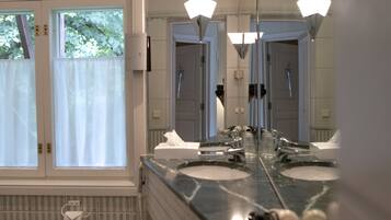 A bathroom with a large mirror, multiple sinks, and a window with a view of trees.