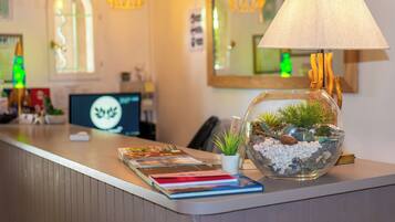 A reception desk with a lamp, a fishbowl with plants, and a computer monitor.