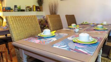 Una mesa de comedor con manteles florales, platos blancos y una taza blanca.