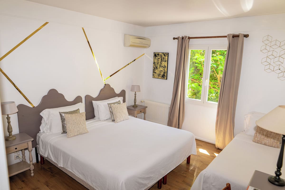Un dormitorio con una cama grande, mesitas de noche, una ventana con cortinas y un radiador.