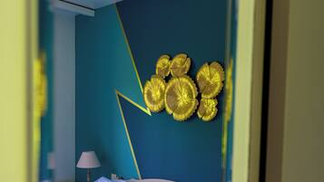 Un dormitorio con cama, almohadas, una lámpara y una decoración en la pared.