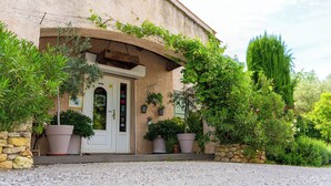 Un edificio con fachada de piedra, una puerta blanca y plantas en macetas alrededor de la entrada.
