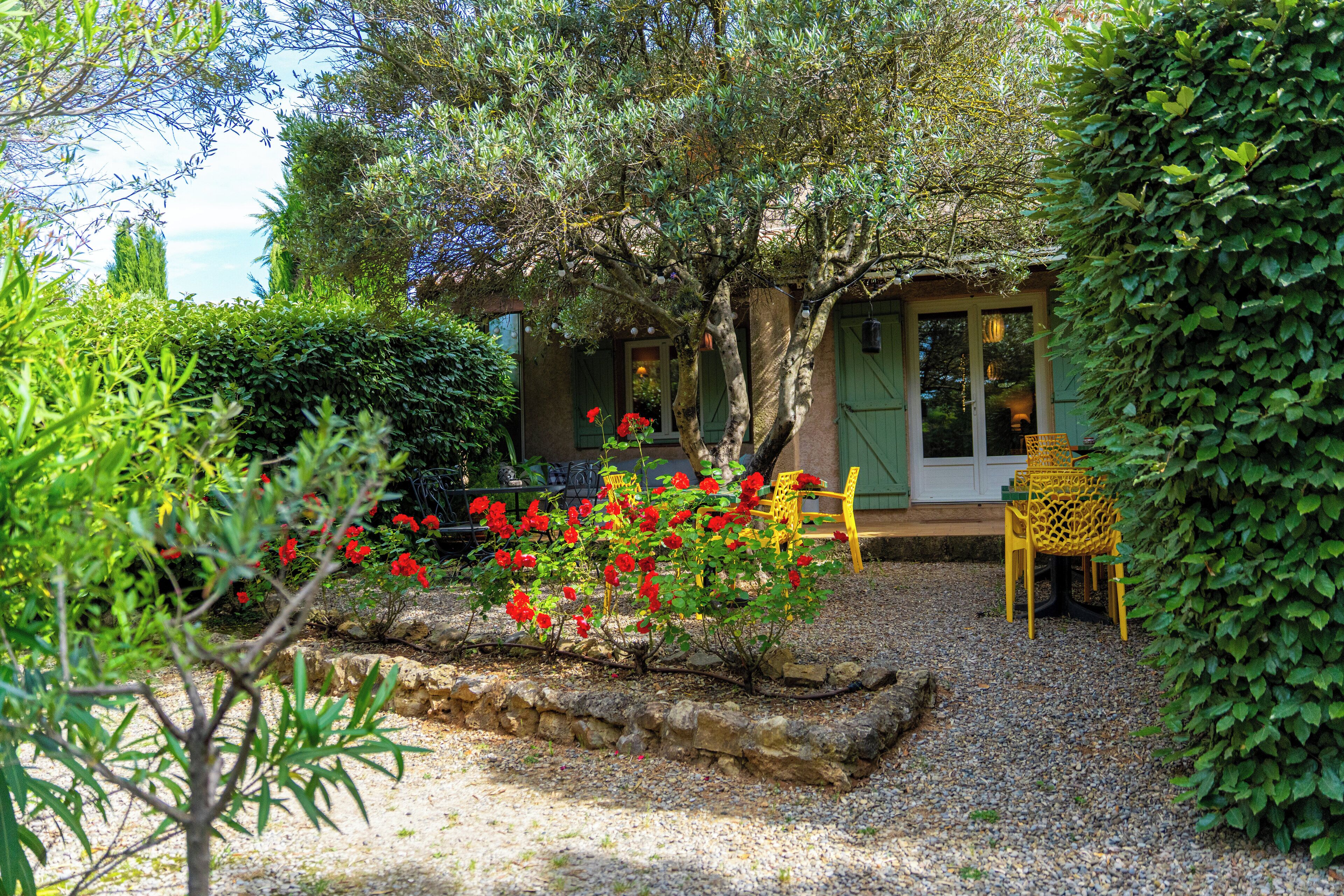 A garden with a gravel path, a yellow chair, and a building with a green door.
