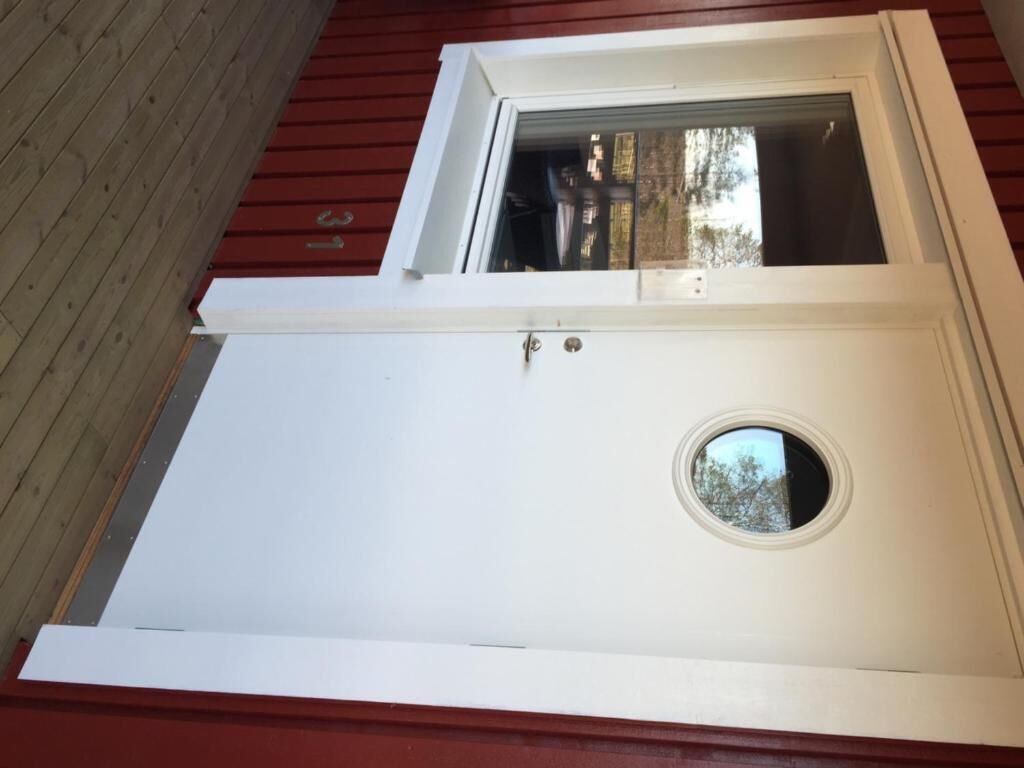 A white door with a circular window and a small doorbell.