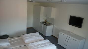 Een hotelkamer met een bed, een bureau, een stoel, een televisie en een kitchenette.
