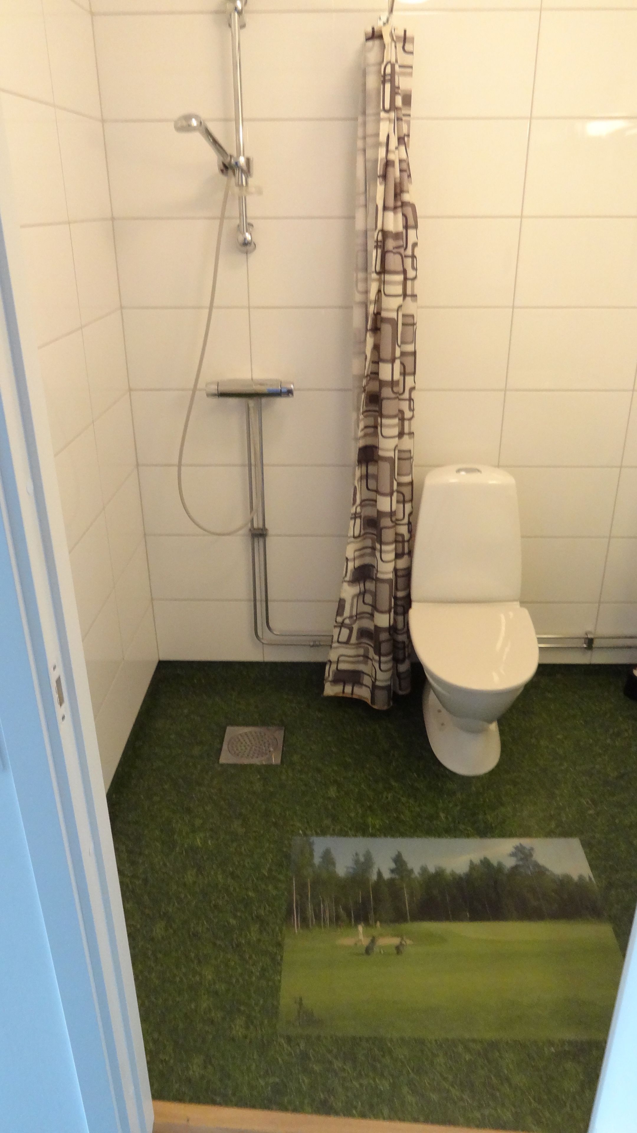 A bathroom with a toilet, shower, and a patterned curtain.