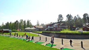 A courtyard with green exercise mats, a red building, and a white tent. - Piteå Golfhotell (Pitea)