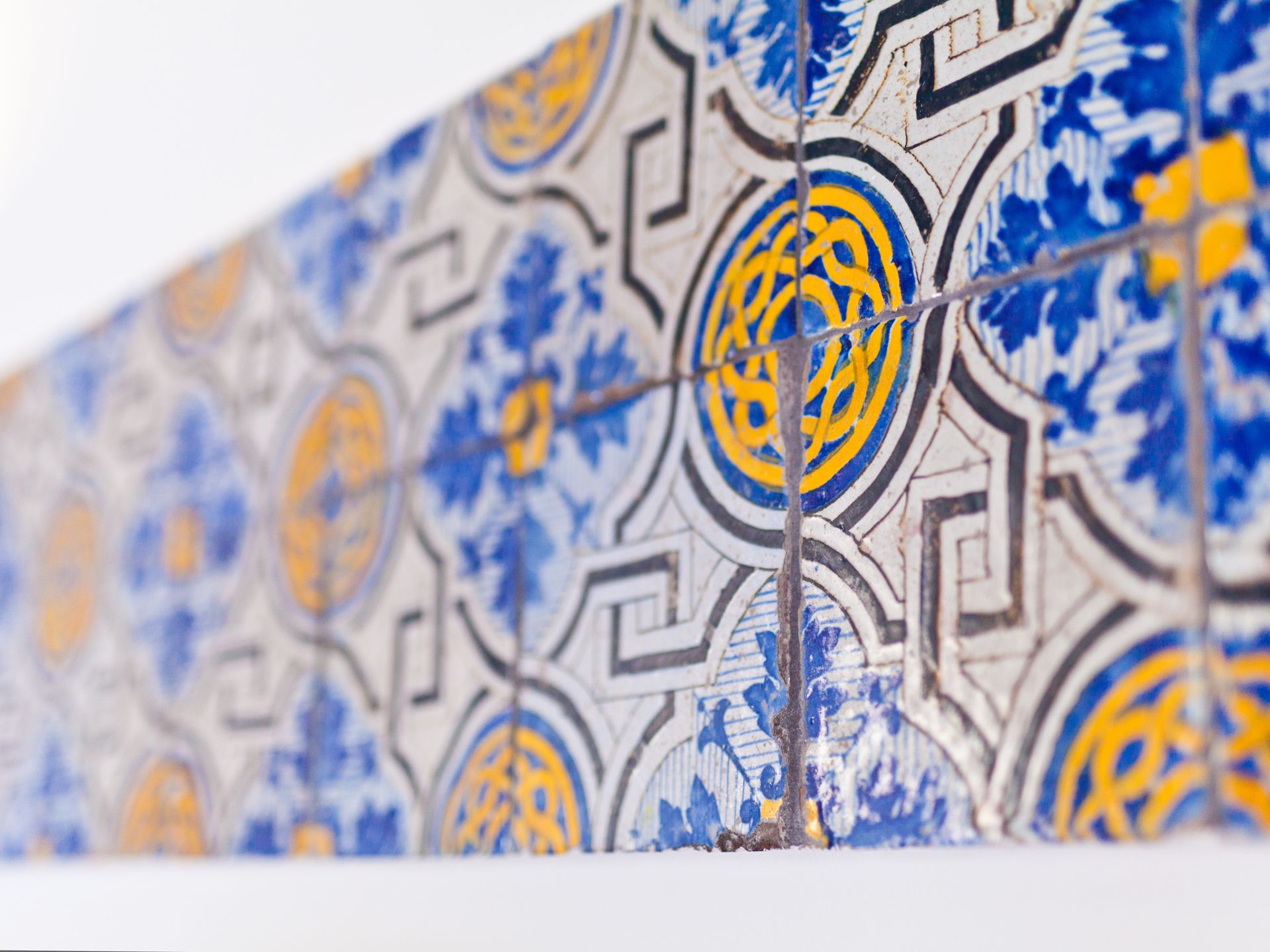A close-up of a tiled wall with geometric patterns and floral motifs.