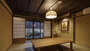 A traditional Japanese room with tatami flooring, a wooden table, sliding doors, and a hanging light fixture. - Kiyomizu Gojo Ntei (Kyoto)