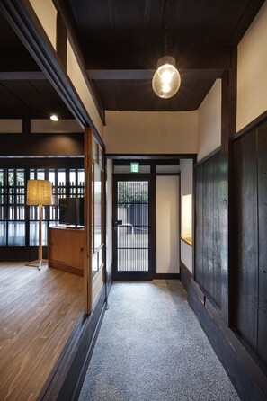 A traditional interior with wooden flooring, a lamp, and a door with a sign.