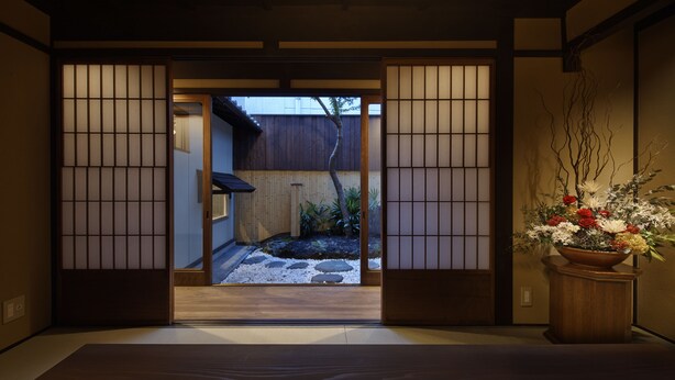 A traditional Japanese interior with tatami flooring, shoji screens, and a wooden door leading to an outdoor garden. - Kiyomizu Gojo Ntei (Kyoto)