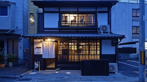 A traditional Japanese building with a wooden gate, a small porch, and a visible air conditioning unit. - Kiyomizu Gojo Ntei (Kyoto)