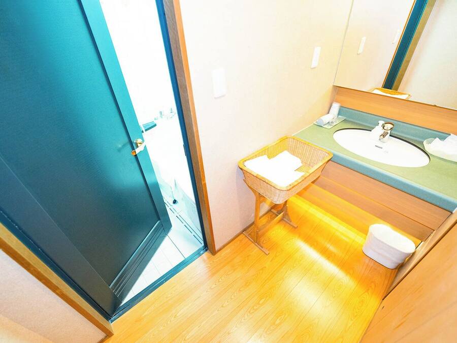 A compact bathroom with a sink, mirror, and a small wicker basket.