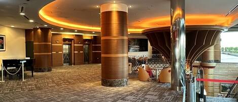 A spacious lobby with a patterned carpet, large cylindrical columns, and a curved ceiling with recessed lighting.