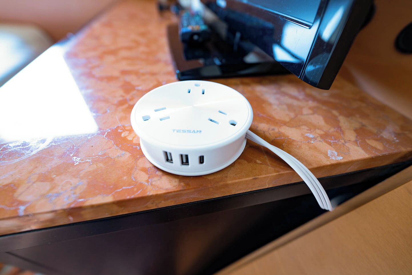 Una ciabatta multipresa bianca con diverse porte USB su un piano di marmo.