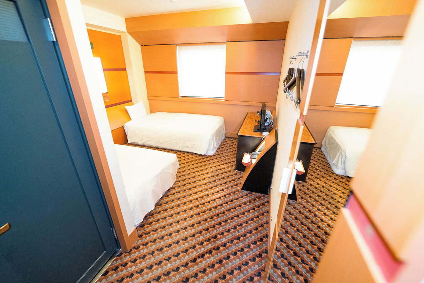 Een kleine hotelkamer met twee bedden, een tafeltje en een raam.