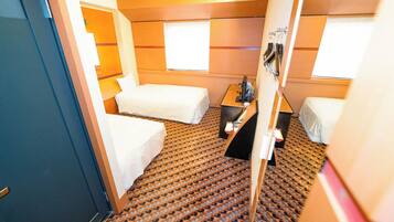 Een kleine hotelkamer met twee bedden, een tafeltje en een raam.