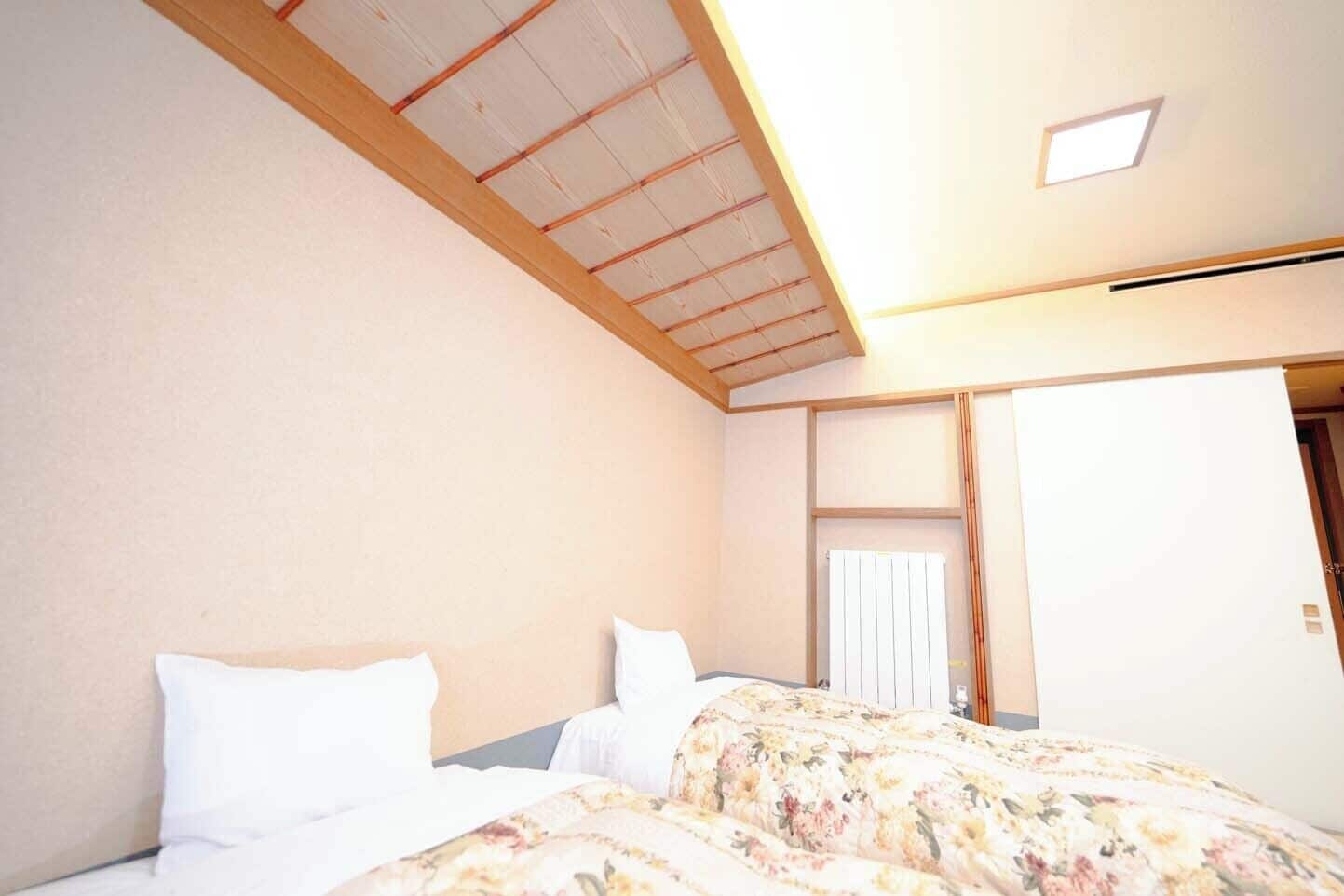 A bedroom with a sloped ceiling, a bed with floral bedding, and a white door.