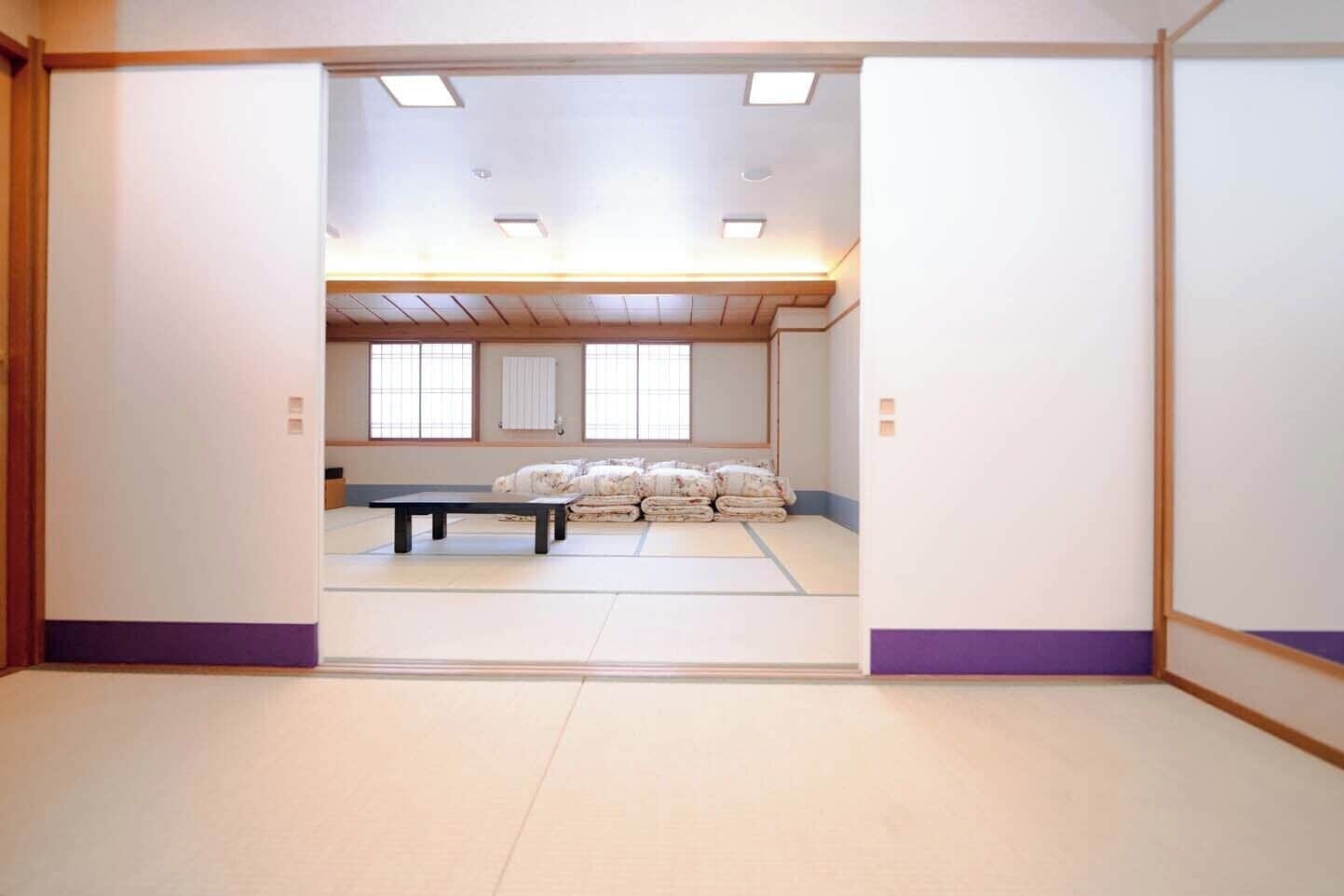 A room with tatami flooring, a low table, and futons in the background.