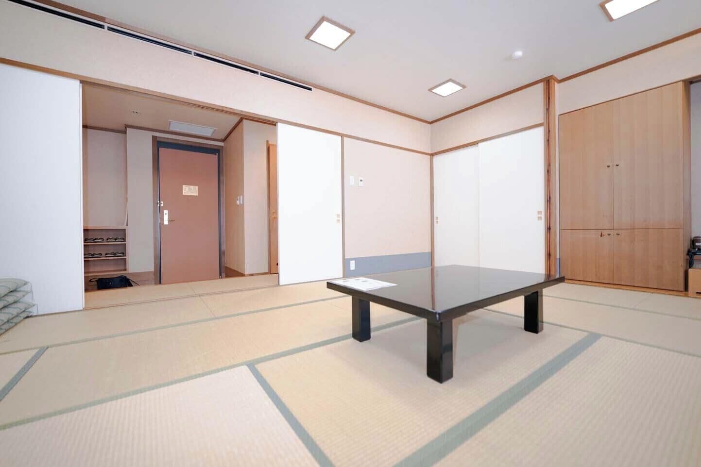 A tatami mat room with a low table, sliding doors, and a wardrobe.
