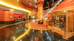 A hotel lobby with a curved floor, a reception desk, a staircase, and a display case with cultural artifacts. - Hotel KOYO (Hashima)